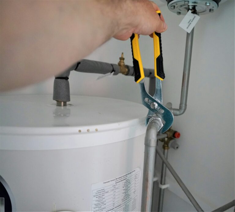 Plumber servicing a water heater with a wrench