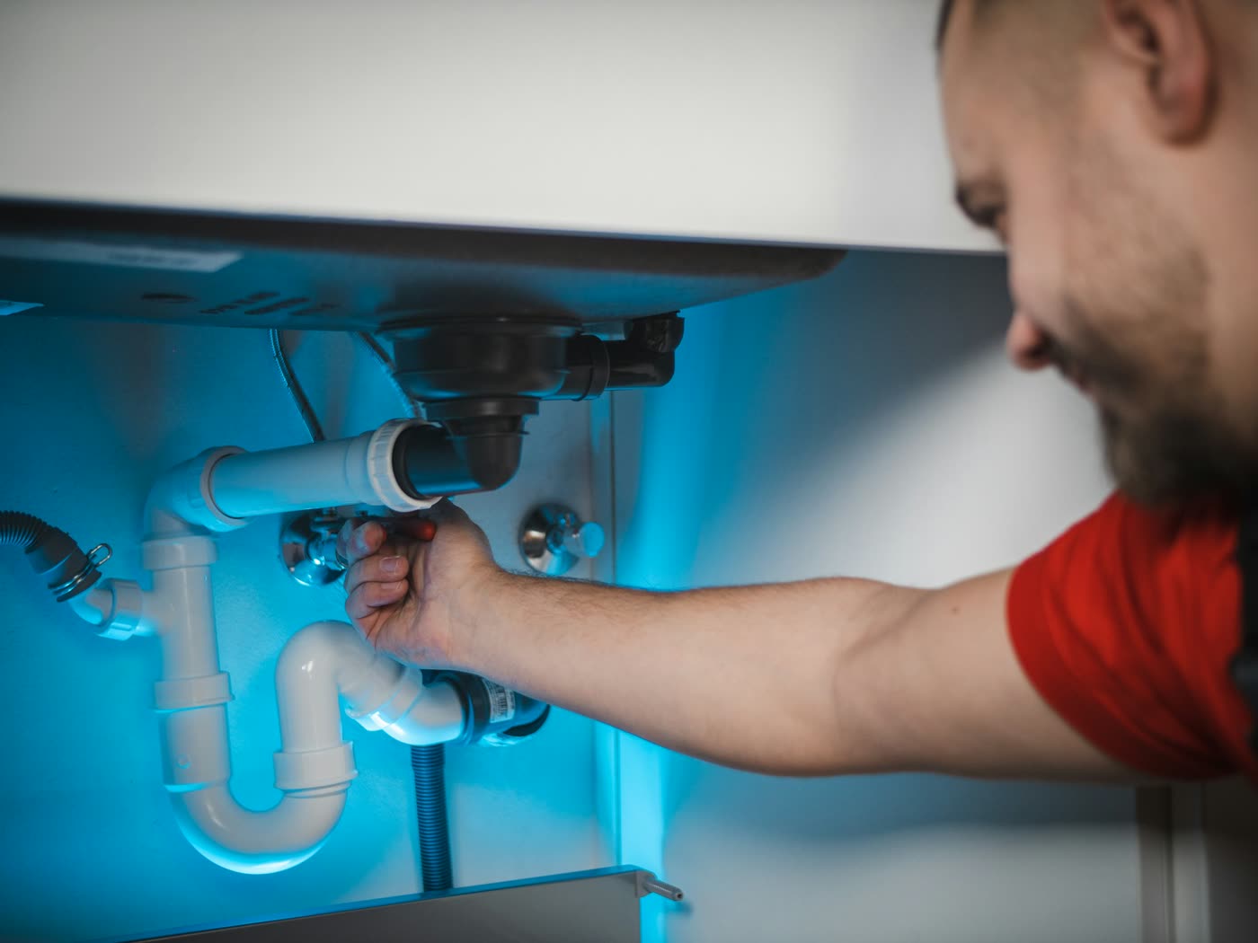 Plumber repairing the drain pipes under a sink